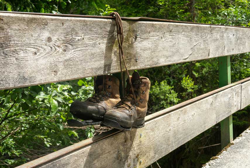 A Pair of Walking Boots Tied to a Wooden Bridge