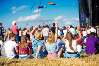 Large Group of People sat down and standing at a Festival with Flags Flying