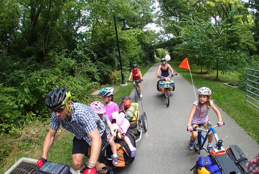 A family on a large bicycle with others enjoying a bike ride