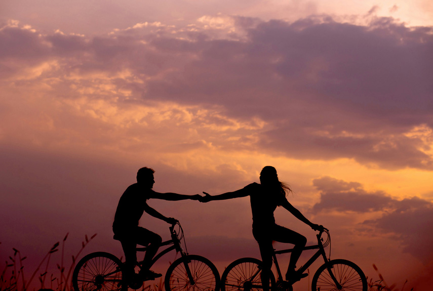 A Couple Riding Bikes as the Sun is Setting