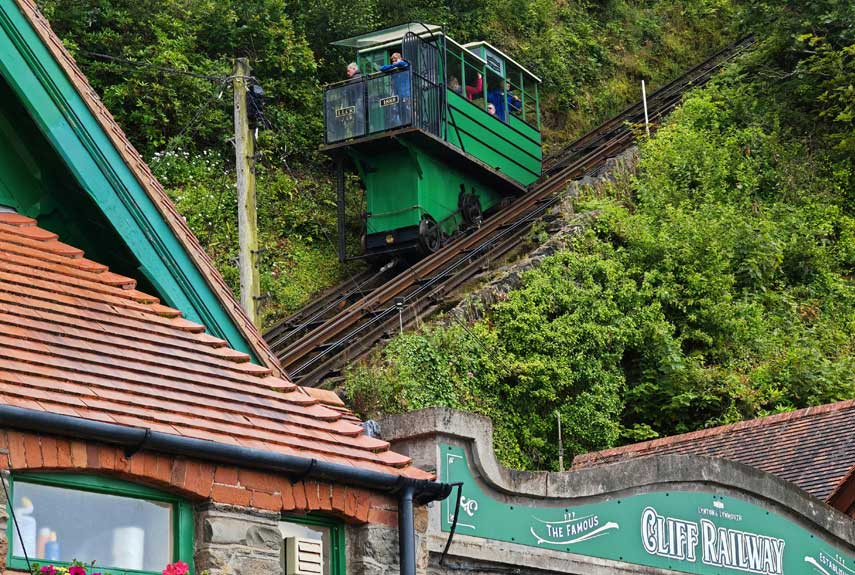 A Rail Cart moving along a steep hill with People enjoying the ride & views