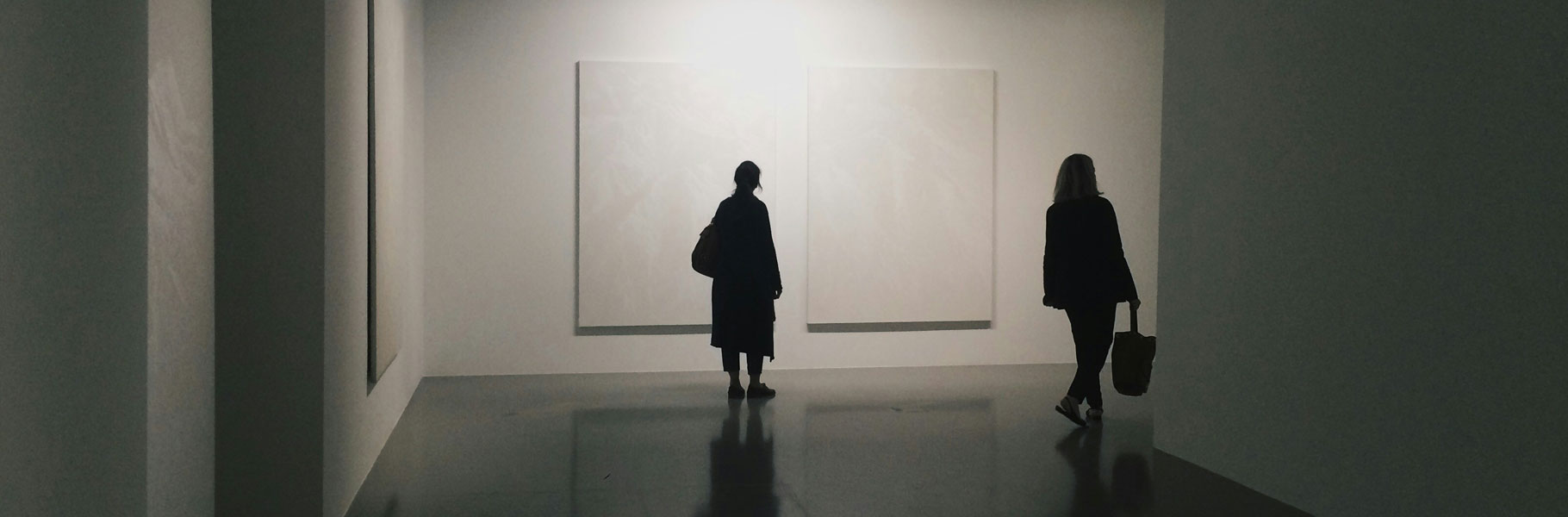 People Walking Through a Museum with White Walls & Artwork