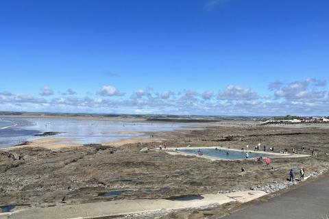 People in a Sea Pool with the Beach and Rolling Green Hills of North Devon in the Background
